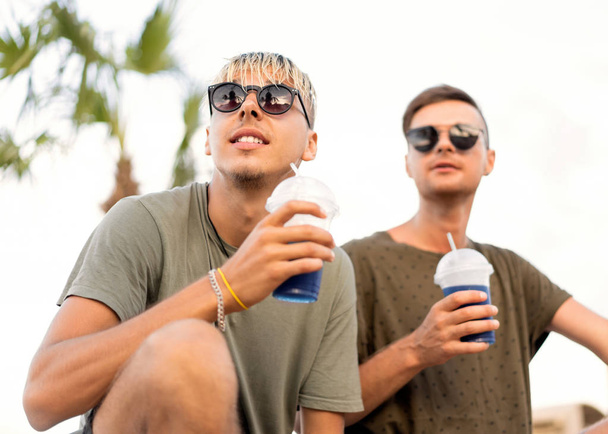 two guys drink cocktails on a tropical beach - Fotoğraf, Görsel