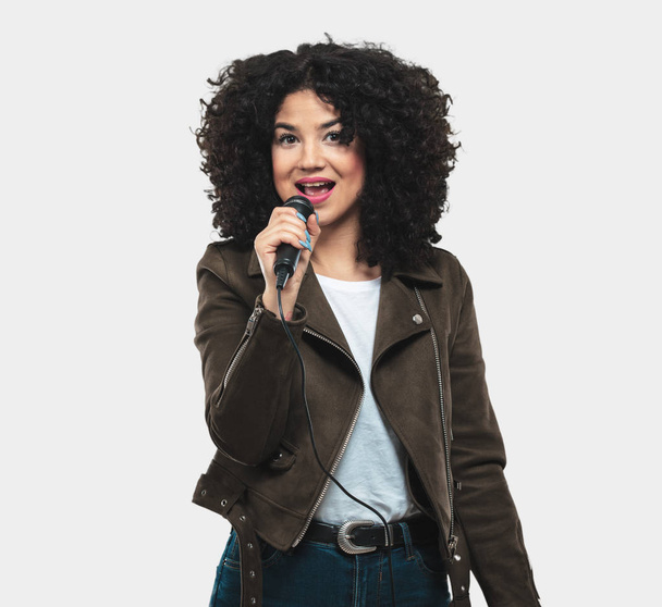 mujer joven sosteniendo un micrófono y cantando
 - Foto, Imagen