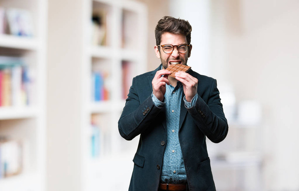 mladý muž jíst čokolády na rozostřeného pozadí - Fotografie, Obrázek