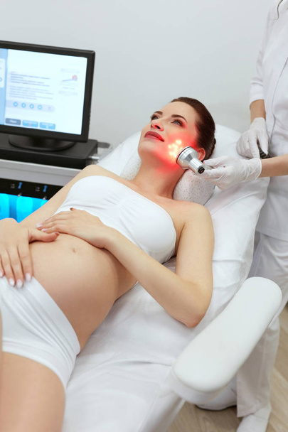La cosmétologie. Femme enceinte faisant de la thérapie à la lumière rouge à la clinique
 - Photo, image