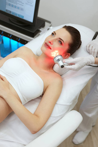 Red Led Light Treatment. Woman Doing Facial Skin Therapy  - Фото, зображення