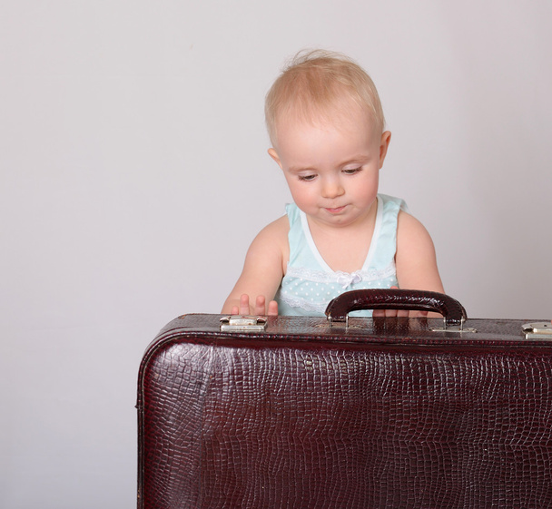 dziecko dziewczynka gra z walizką na szarym tle - Zdjęcie, obraz