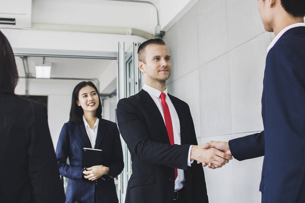 Manager, Geschäftsmann, europäischer Investor oder Chef schütteln dem asiatischen Unternehmer die Hand und treffen sich mit einem Dolmetscher, der in der Nähe steht und übersetzt. - Foto, Bild
