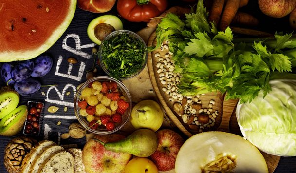 Foods rich in fiber as rye galette , bread, watermeon, wheat bran, beans , almonds, seed, pears, plum bananas, cranberry, raspberries, pistachios, red pepper kiwi walnuts melon celery carrot Wooden table as background - Photo, Image
