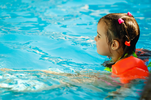 Продумана дівчинка в басейні, на відкритому повітрі
. - Фото, зображення