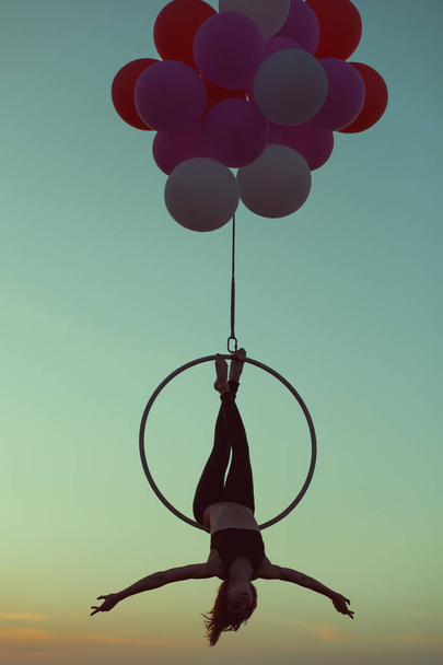 Ginasta realiza acrobacias acrobáticas no ringue. Balões segurar o anel no ar
. - Foto, Imagem