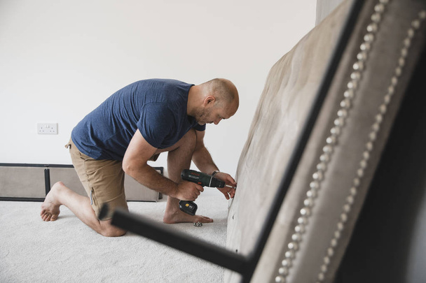 Mature man is building a bed in his new home.  - Fotografie, Obrázek