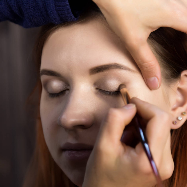 makeup artist preparing young beautiful woman. close-up eyeliner - Foto, afbeelding