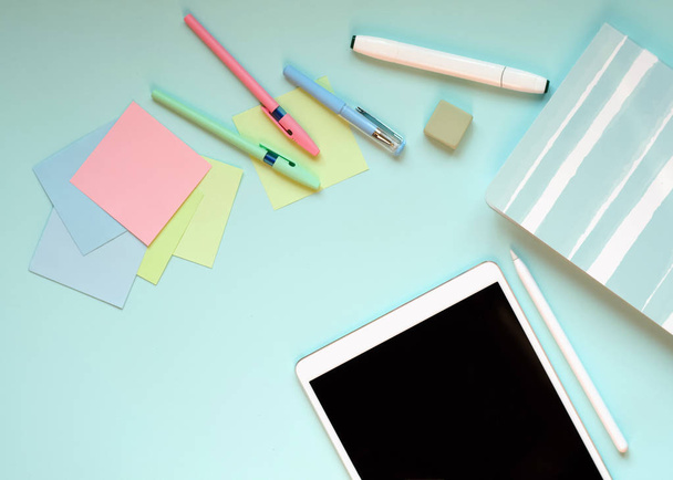 Pen, tablet, stickers and Notepad lie on a blue background. - Фото, изображение