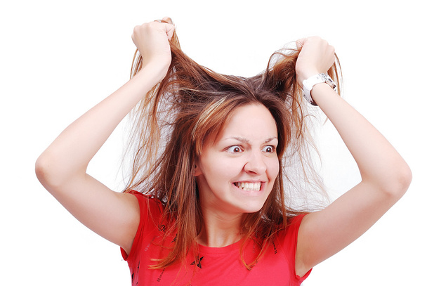 Young female model grabbing her hair with angry expression on face - Photo, image