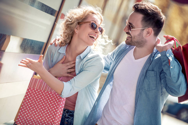 Hermosa pareja amorosa joven llevando bolsas de compras y disfrutando juntos. Concepto de consumismo
. - Foto, imagen