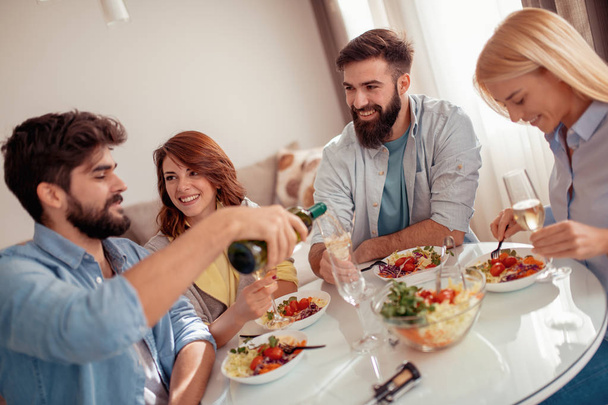 Groep vrienden eten wat gezond eten thuis en hebben een geweldige tijd samen. - Foto, afbeelding