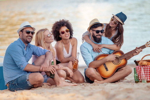 Група щасливих молодих людей розважаються разом, грають на гітарі
. - Фото, зображення