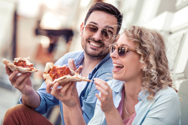 Retrato de um casal feliz. Eles estão rindo e comendo pizza e se divertindo muito
. - Foto, Imagem