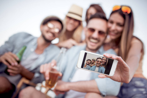 Verano, vacaciones, vacaciones y concepto de felicidad - grupo de amigos tomando selfie con el teléfono inteligente. - Foto, Imagen