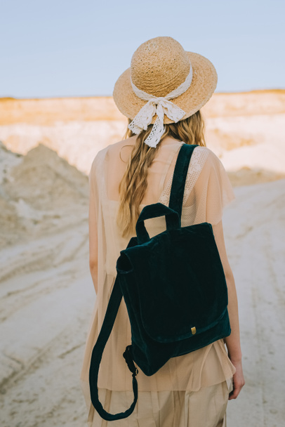back view of girl in straw hat walking with backpack in sandy canyon - Foto, Imagen
