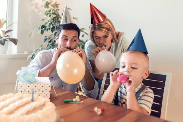 Koncepcja ludzie i wakacje - szczęśliwą rodzinę, dmuchanie balonów w domu. - Zdjęcie, obraz