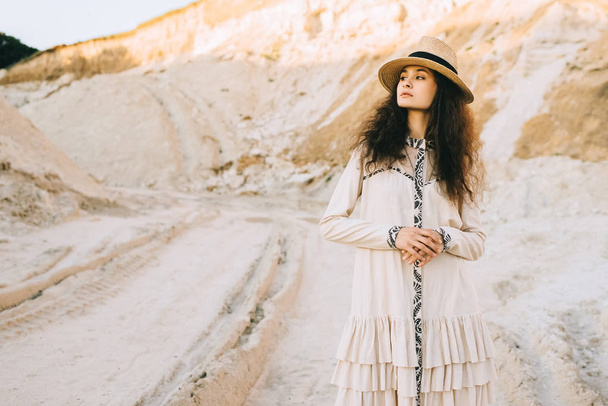 gyönyörű göndör lány pózol ruha és homokos Canyon szalmakalap - Fotó, kép