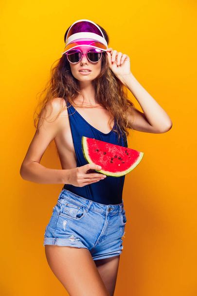Woman in cap and swimwear hold slice of watermelon - Zdjęcie, obraz