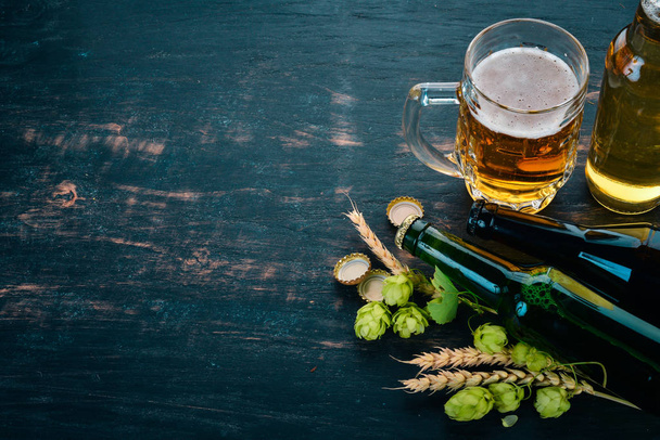 Beer and fresh hops on a black wooden background. Free space for text. Top view. - Foto, Bild