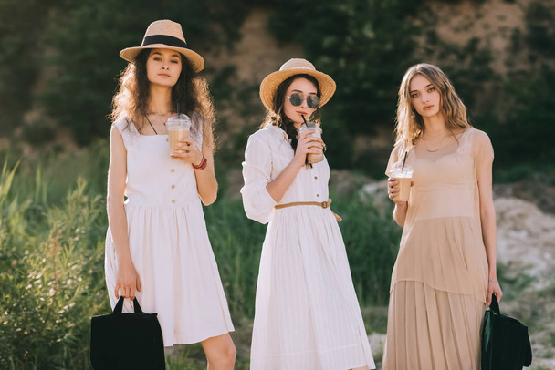attraenti donne alla moda in cappelli di paglia con caffè latte
 - Foto, immagini