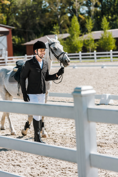 sorridente bella passeggiata equestre maschile vicino al cavallo al club di cavalli
 - Foto, immagini