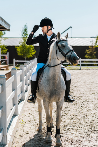 komea mies ratsastus hevonen klubilla ja koskettaa ratsastus kypärä
 - Valokuva, kuva
