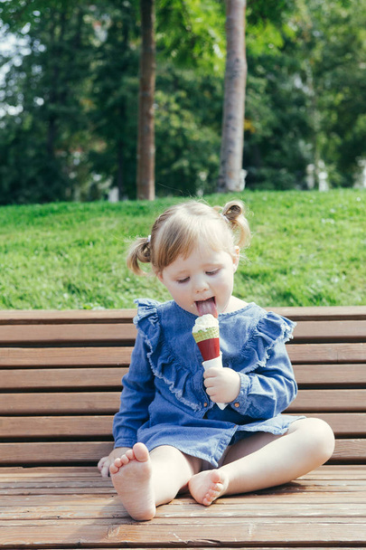 暖かい晴れた日に都市公園でアイスクリームを食べる 3 年古い女の子の肖像画 - 写真・画像