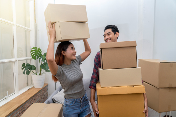 Asian young couple carrying big cardboard box for moving in new house, Moving and House Hunting concept, selective focus - Foto, Imagem
