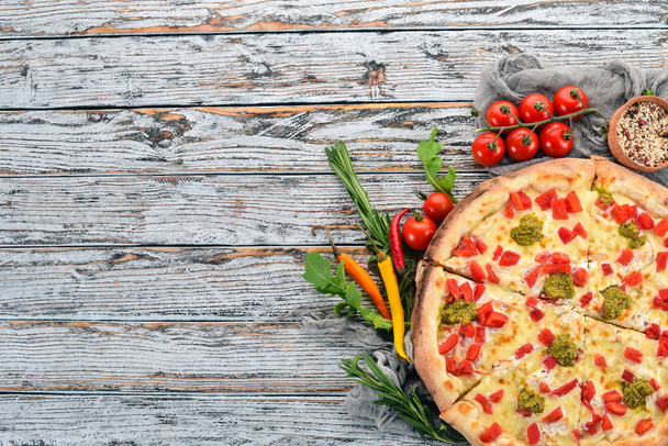 Pizza with pesto sauce and paprika. Italian cuisine. On a wooden background. Free space for text. Top view. - Фото, зображення