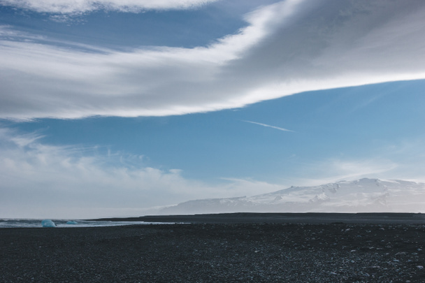 czarnym wulkanicznym piaskiem, na wybrzeżu Oceanu Jokulsarlon, Islandia pod błękitne niebo z chmurami - Zdjęcie, obraz