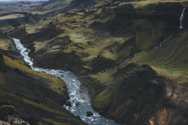 воздушный вид на кривую реку, текущую в зеленых холмах Исландии
 - Фото, изображение