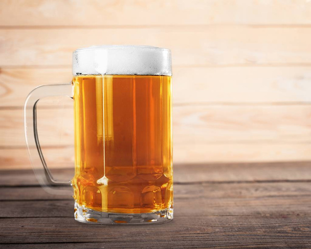 Mug of cold beer on wooden table  - 写真・画像