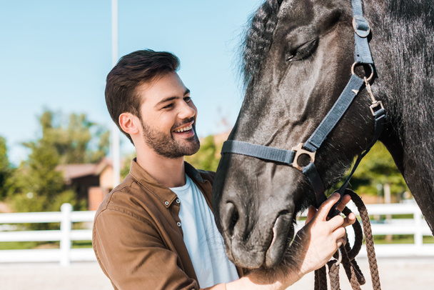усміхнений красивий ковбой, що фіксує коня на половині в кінному клубі
 - Фото, зображення