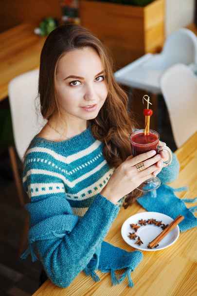 Brown-haired woman drinking smoothie with cinnamon alone in cafe - Fotoğraf, Görsel