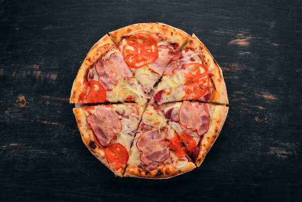 Pizza with bacon, tomatoes and onion. Italian cuisine. On a wooden background. Free space for text. Top view. - Foto, Bild