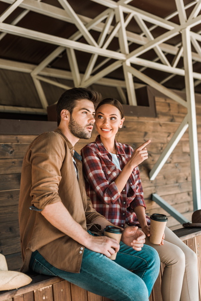 Cowboy en cowgirl zitten met koffie te gaan op de ranch, woman wijzend op iets - Foto, afbeelding