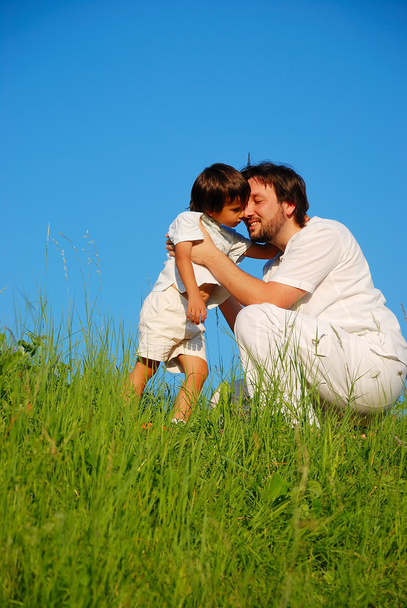 Young father in white with child on beautiful meadow - Фото, изображение