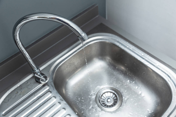 Robinet à longue portée du robinet d'eau avec fuite de goutte d'eau au lavabo vers les eaux usées
 - Photo, image