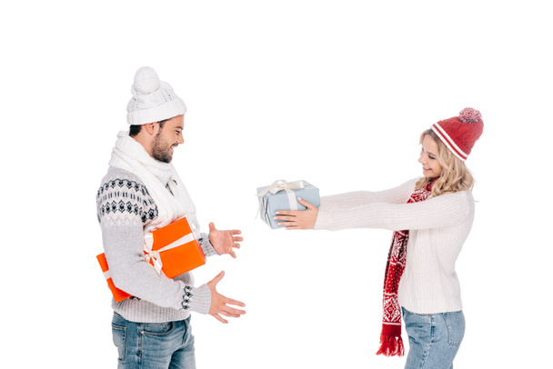 vista lateral de feliz pareja joven presentando cajas de regalo aisladas en blanco
 - Foto, Imagen