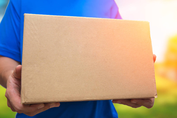 man met bruine doos pakket levering schip naar zijn huis uit online winkelcentrum - Foto, afbeelding