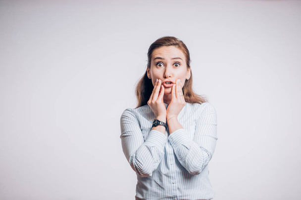 Toothache problems. Young brunette woman with two hands holding her cheeks and looking at the camera on white background - 写真・画像