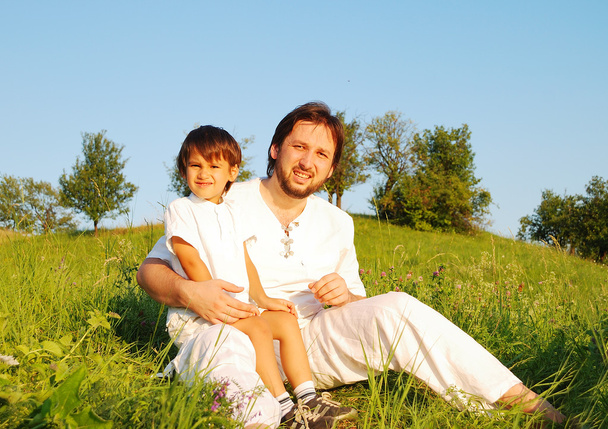 Young father in white with child on beautiful meadow - Fotó, kép
