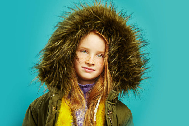 sweet child in autumn jacket with big fur hood in green. - Foto, imagen