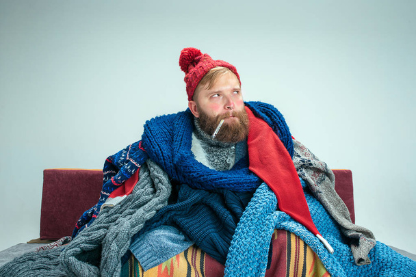 Bearded Man with Flue Sitting on Sofa at Home. Healthcare Concepts. - Fotó, kép