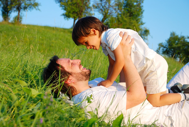 Young father in white with child on beautiful meadow - Foto, afbeelding