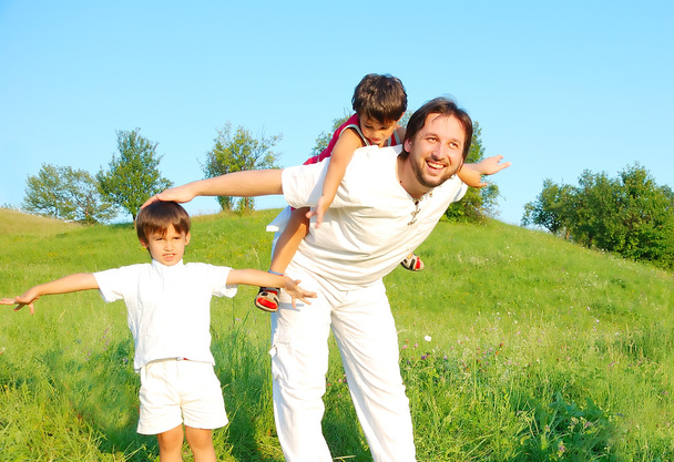 Молодой отец в белом с мальчиками на прекрасном лугу
 - Фото, изображение
