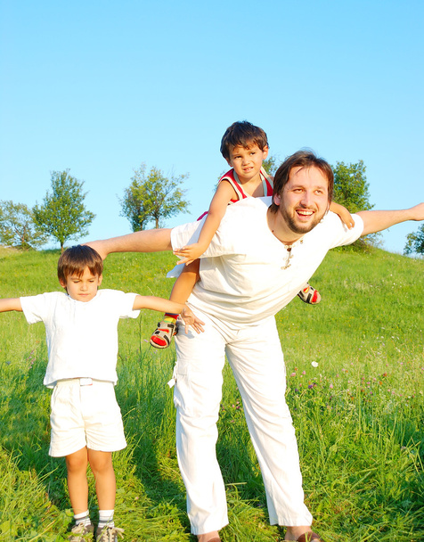 Young father in white with boys on beautiful meadow - Foto, immagini