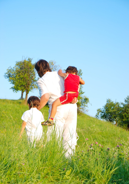 Young father in white with boys on beautiful meadow - Фото, изображение