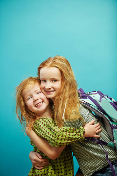 Two red haired child sister cute hugging isolated on blue background. - Фото, зображення